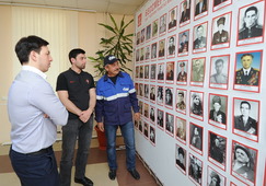 Работники предприятия у стенда с фотографиями ветеранов